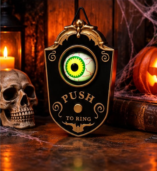 Eyeball Doorbell on a table beside a skull, a candle and a pumpkin
